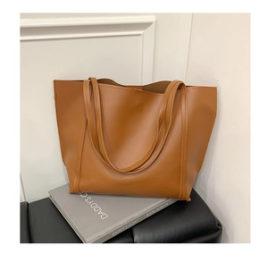 Detail of caramel leather tote bag with fine stitching and slim shoulder straps