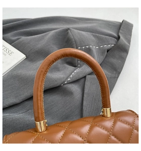 Macro view of brown quilted leather texture and premium gold metal link on handbag