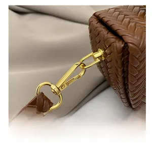 Close-up of brown woven saddle bag with premium gold lobster clasp and metal hardware