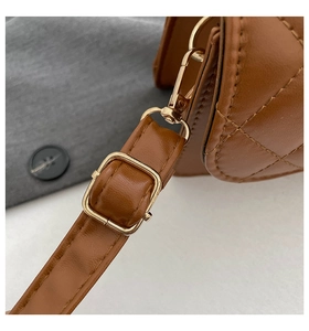 Detail of brown quilted leather bag with gold hardware and adjustable strap buckle