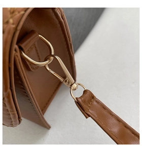 Close-up of golden metal lobster clasp and quilted brown leather shoulder bag detail