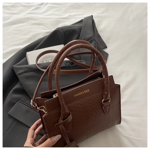 Detail of brown faux leather handbag with crocodile pattern and dual top handles