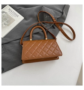 Detail of brown quilted faux leather handbag with gold hardware and top handle