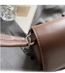 Close-up of brown leather bag with golden metal buckle and detailed stitching