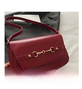 Detail shot of burgundy shoulder bag with golden horsebit buckle and metal rivets