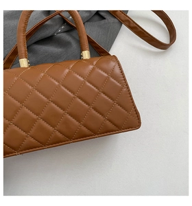 Detailed close-up of brown quilted faux leather texture with golden metal hardware