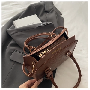 Detailed close-up of dark brown crocodile texture leather bag with gold metal hardware