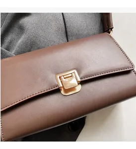 Close-up of brown leather bag with golden rectangular metal lock and smooth texture