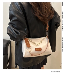 Détail du sac bandoulière en nylon blanc avec chaîne dorée et sangle en cuir marron