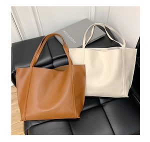 Detail view of large faux leather tote bags in caramel brown and beige colors