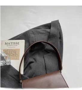 Detail of elegant dark brown leather handbag with rounded handle and flap closure