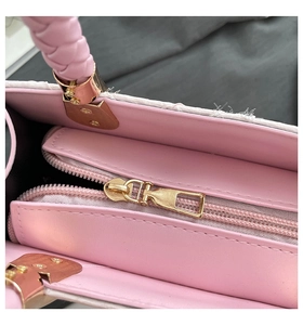Detailed interior of pink handbag featuring a smooth lining and golden metal zipper pocket