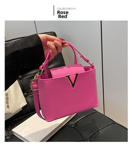 Detail of rose red pebble leather handbag featuring a golden V-shaped metal logo