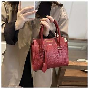 Close-up of red snakeskin texture handbag with gold fashion lettering and double handles