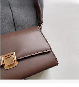 Detailed macro view of the dark brown leather flap bag with elegant gold rectangular clasp