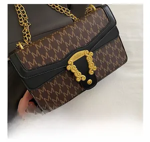 Close-up of golden vintage engraved clasp and monogram pattern on plaid chain bag