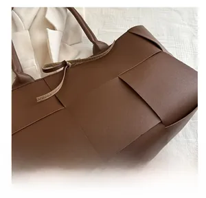 Nahaufnahme der braun gewebten Leder-Tote-Tasche mit dekorativem Kordelzug-Detail
