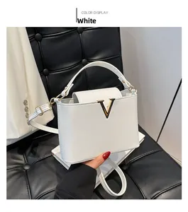 Detailed shot of white pebbled leather bag with metal V-logo and matching top handle