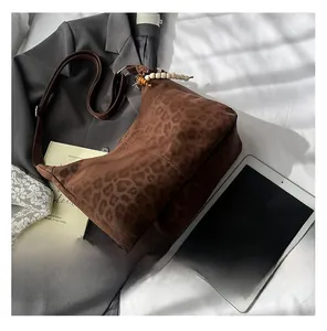 Close-up of leopard print tote bag with wooden bead charm and suede texture detail