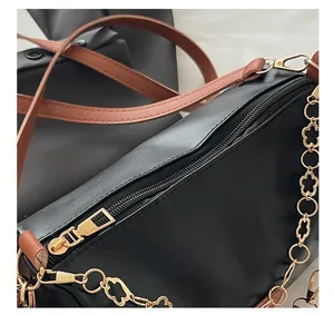 Gros plan du sac bandoulière noir avec fermeture éclair et chaîne à fleurs dorées