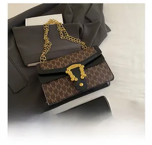 Close-up of vintage monogram canvas handbag with gold embossed clasp and chain strap