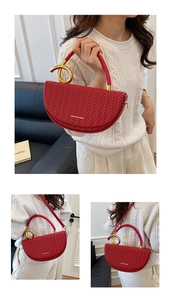 Detail showing red saddle bag with woven texture, golden ring handle and crossbody strap
