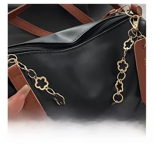 Gros plan du sac à main noir avec chaîne à fleurs dorées et détails de la poignée