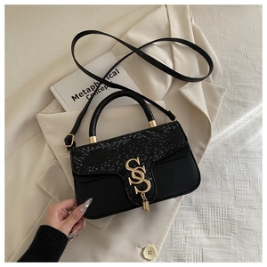 Detail of black crossbody bag with snake texture flap and gold double S buckle