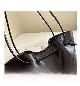 Dettaglio della borsa tote in pelle cerata marrone scuro con coulisse e finitura lucida