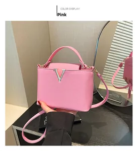 Detail of pink bucket bag with a metal V-shaped buckle and fine grained leather texture