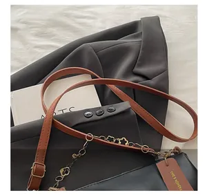 Détail de la bandoulière en cuir réglable et chaîne dorée sur un sac à bandoulière noir