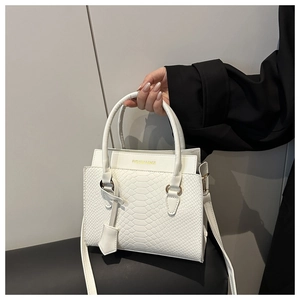 Detail of white faux snake pattern texture on leather handbag with gold lettering