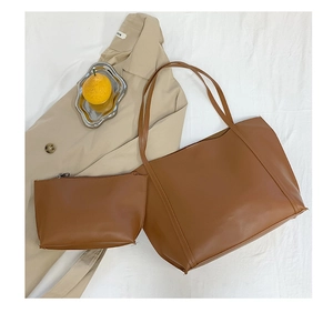 Detail view of brown faux leather tote and matching zipper pouch on beige coat background