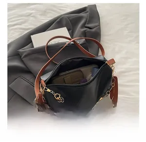 Détail du sac polochon noir avec chaîne à fleurs dorées montrant sa grande capacité