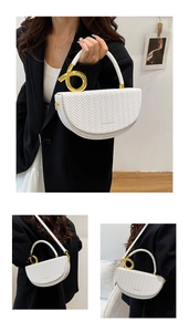 Detail of white woven saddle bag with gold metal ring and detachable shoulder strap