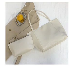 Minimalist beige faux leather tote bag set with matching zipper pouch on white cloth