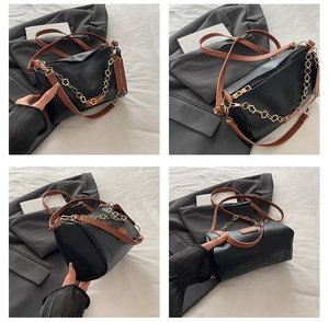 Détail d'un sac Boston noir avec des lanières brunes et une chaîne trèfle dorée