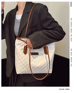 Detail of white quilted tote bag with brown straps and FASHION & BAGS leather label
