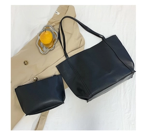 Detail view of black vintage PU leather tote bag set with matching zipper pouch on white fabric