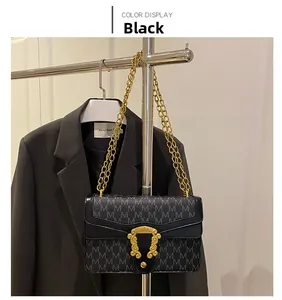 Detail of black leather shoulder bag with gold chain strap and vintage metal clasp