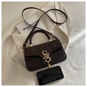 Close-up of brown faux leather crossbody bag with snake-embossed flap and gold S buckle