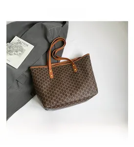 Detail of M-pattern monogram tote bag with brown straps and golden rivets reinforcement