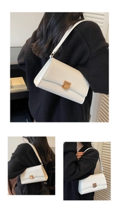 Detail of white baguette bag with matte leather and a gold brushed metal twist lock