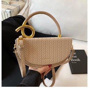 Detail of beige woven saddle bag with gold ring handle and FASHION & BAGS logo