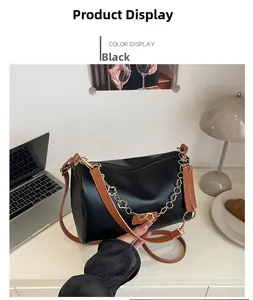 Détail du sac bandoulière noir avec chaîne à fleurs dorées et bandoulière en cuir