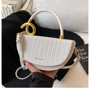 Close-up of white woven saddle bag with gold ring hardware and luxury texture detail