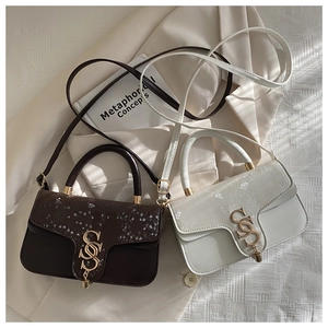 Detail of snake-texture leather crossbody bags with golden S-buckle on beige blazer