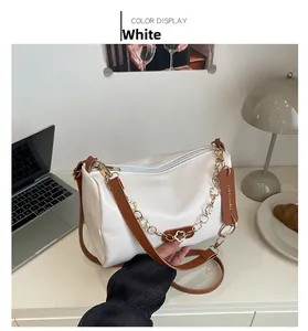 Gros plan sur le sac Boston en cuir blanc avec chaîne dorée florale et bandoulière