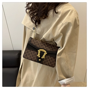Detail of vintage flap bag featuring M-pattern jacquard and gold buckle on a model