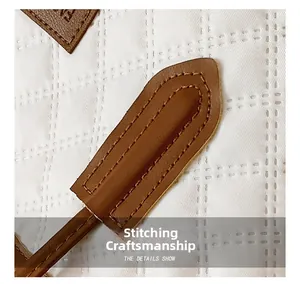 Detail showing high-quality quilted stitching and leather strap attachment on white tote